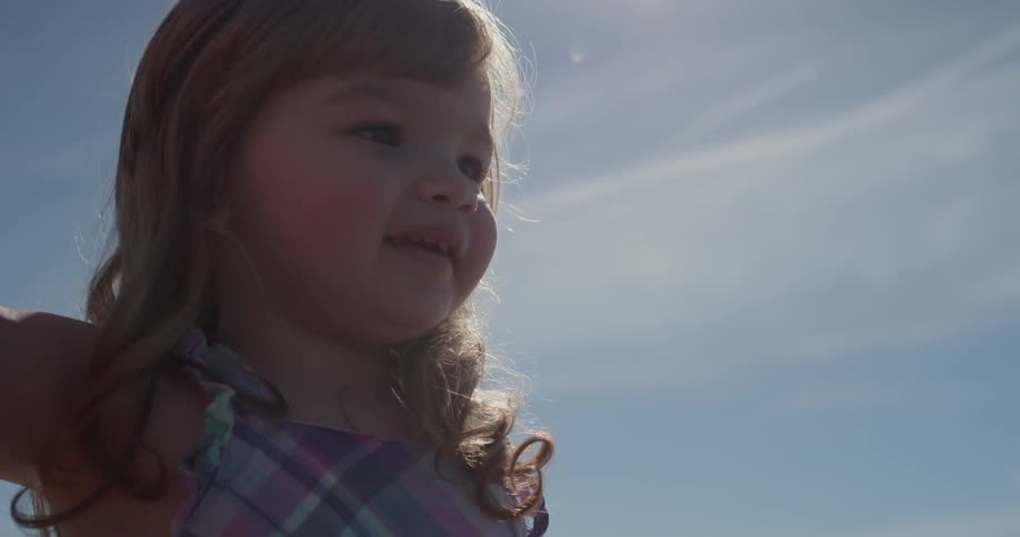 Child stands outside smiling on a sunny day