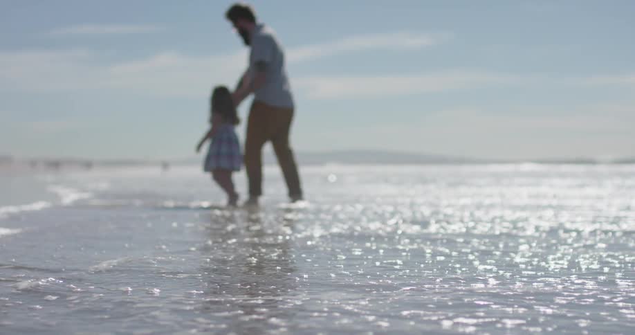 A man and young girl play as the tide rolls in