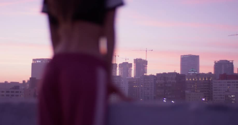 A woman leans on the railing of a building rooftop