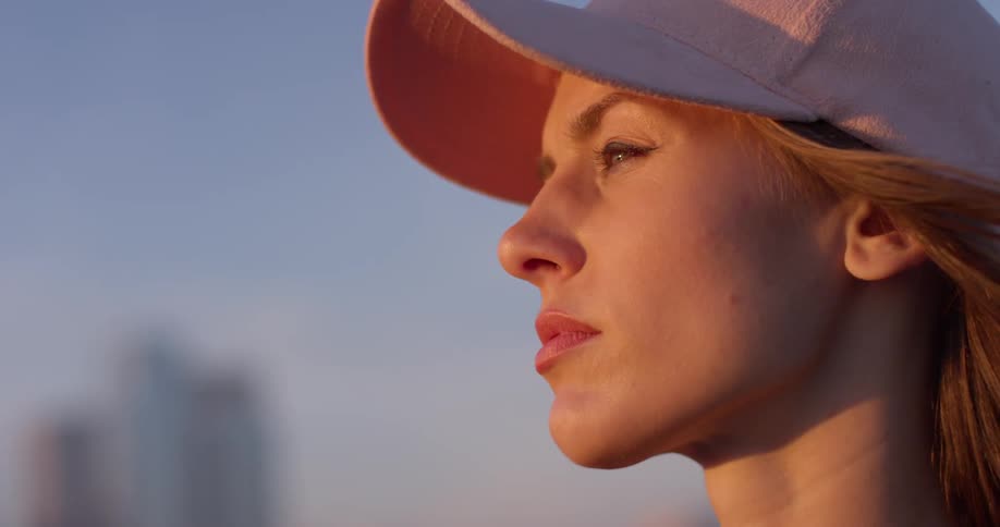 A woman in a pink hat stands atop a rooftop