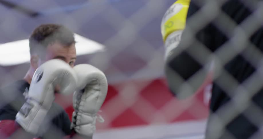 A man walks behind the fence in the gym before boxing