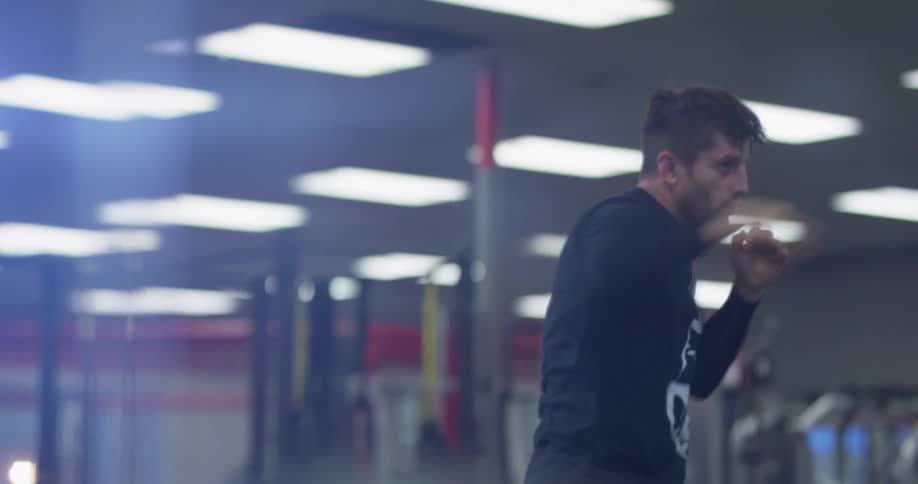 A man is shadow boxing inside a gym during the day