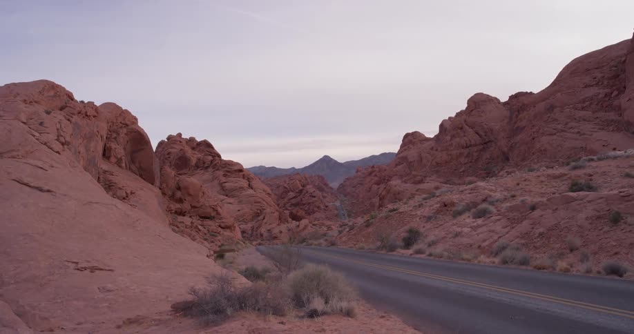 A road is leading through a desert landscape on a cloudy day