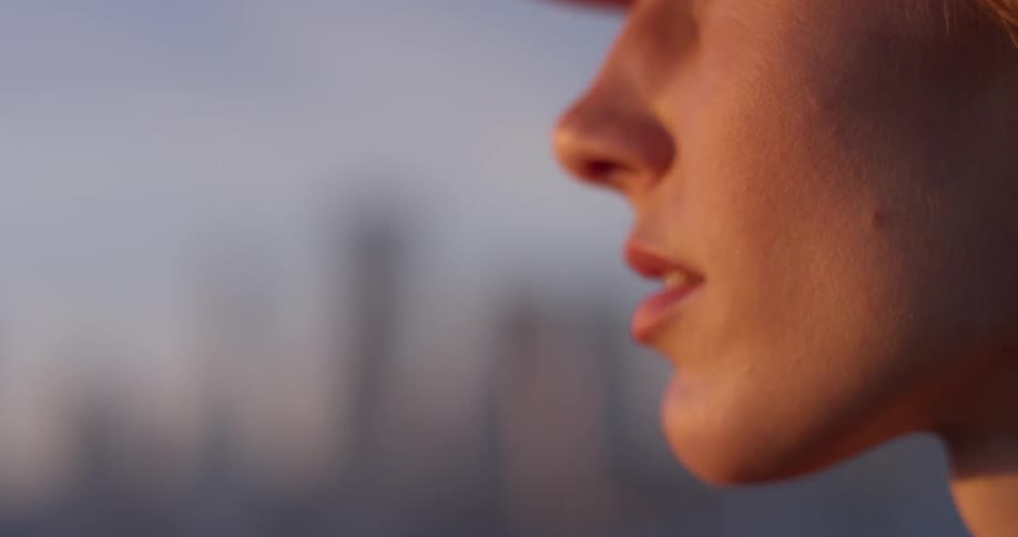 A woman in a hat looks out towards the sun