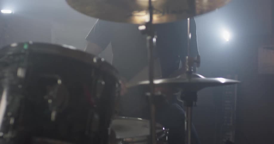 A drummer is playing drums indoors in daylight