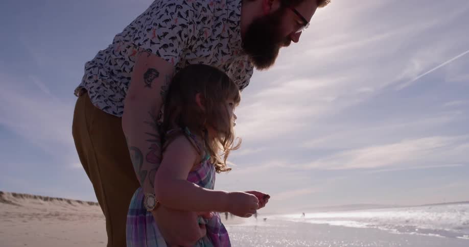 A man and young girl play on the beach