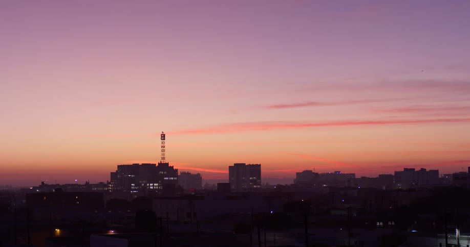 Thin clouds are hovering in the sky above a city at dusk