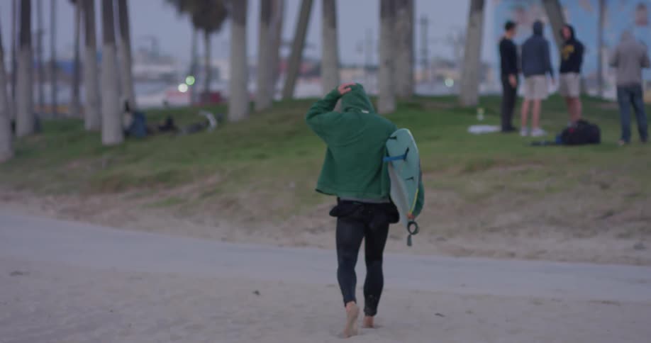 A person carries their surfboard across the trail
