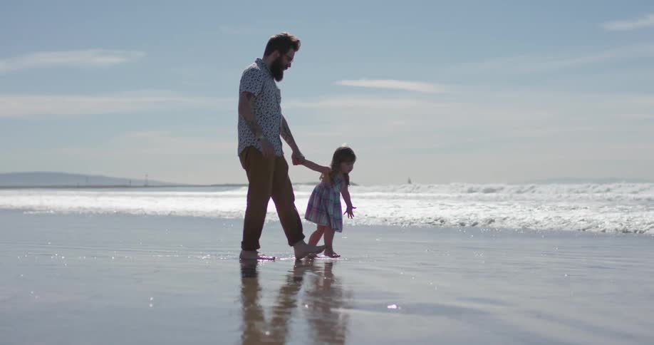A man and young girl play on the wet sand