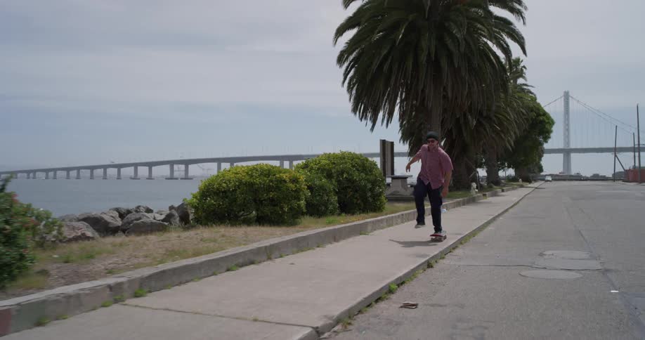 A man rides a skateboard on a sidewalk