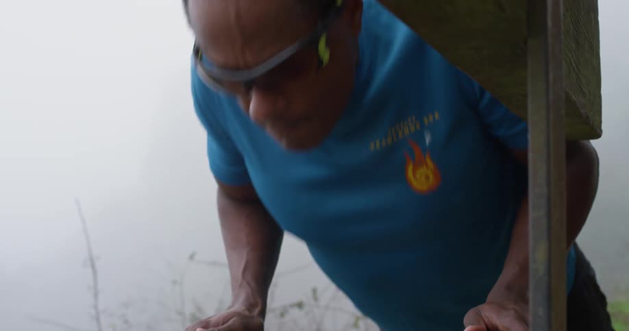 A man does push ups outside on a bench on a foggy day