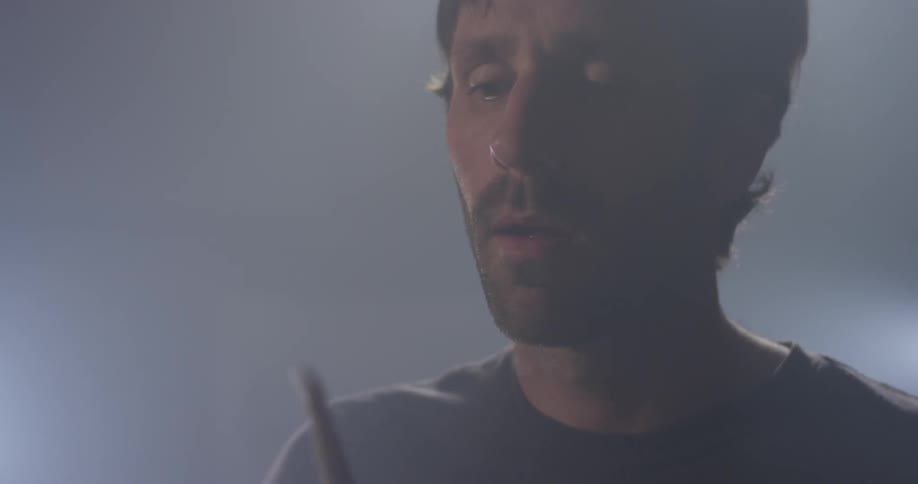 A light shines behind a man playing drums