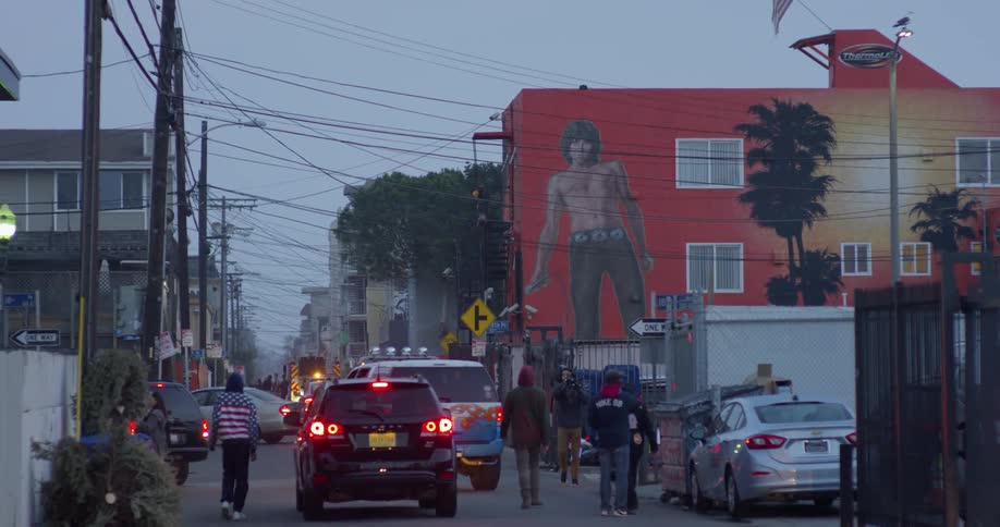 People and cars travel on a city neighborhood street