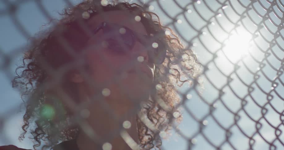 A man is looking through a fence outside on a sunny day