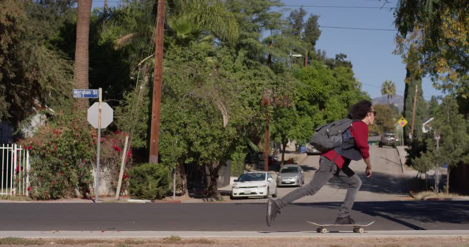 Boy is riding skateboard on neighborhood street on sunny day