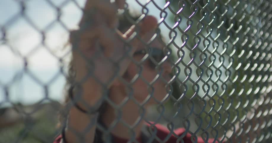 A person is leaning on the chain link fence