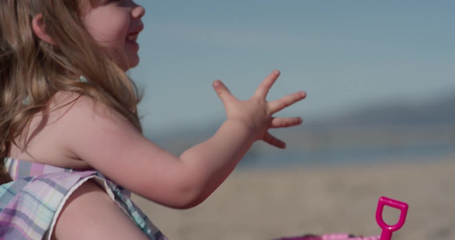 A young girl plays in the sand on the beach