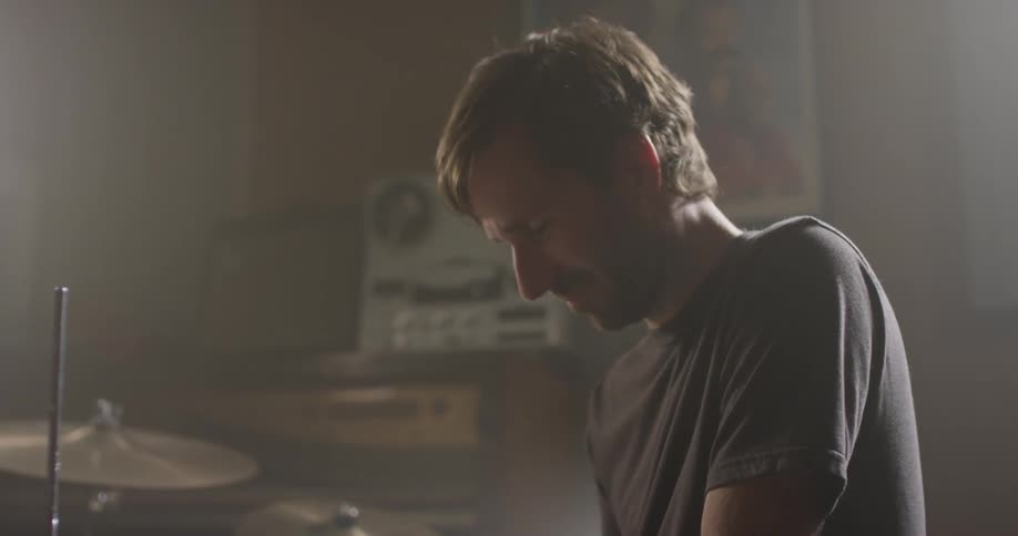 A man uses his phone as he sits at the drum kit
