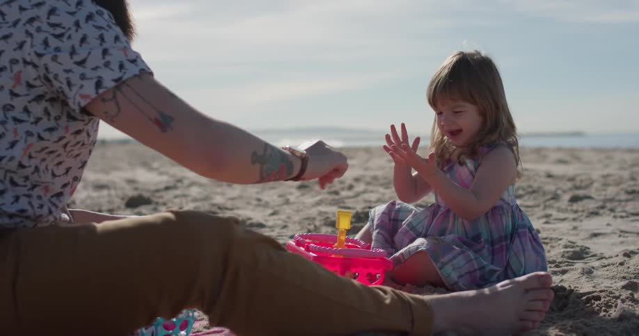 Man and child play in the sand on the beach