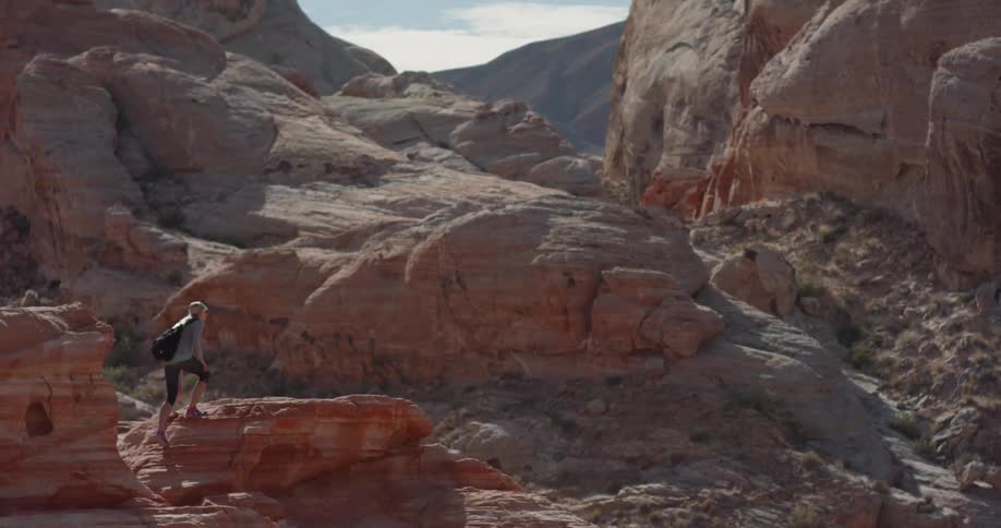 Woman climbs up over rocky terrain on a sunny day