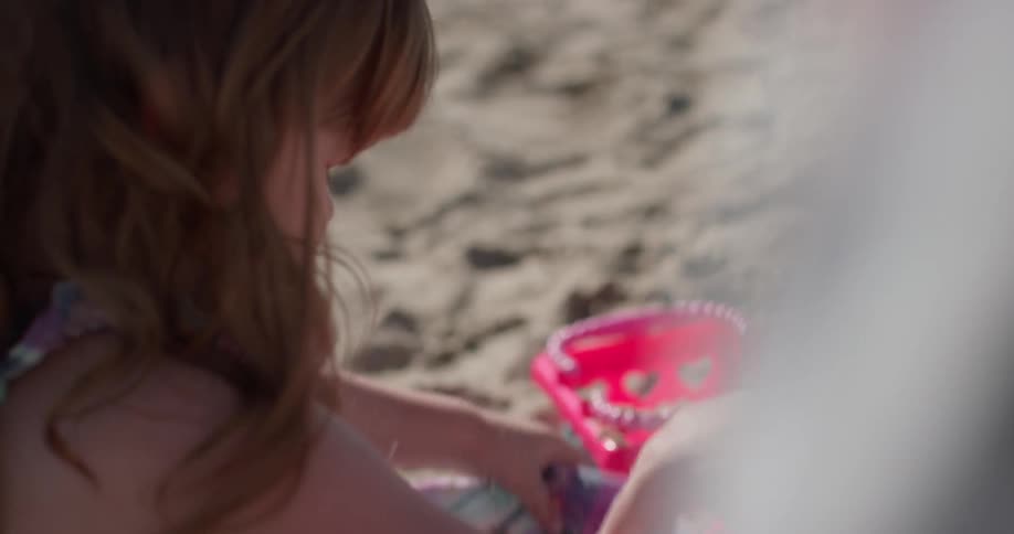 Child plays with sand on her dress