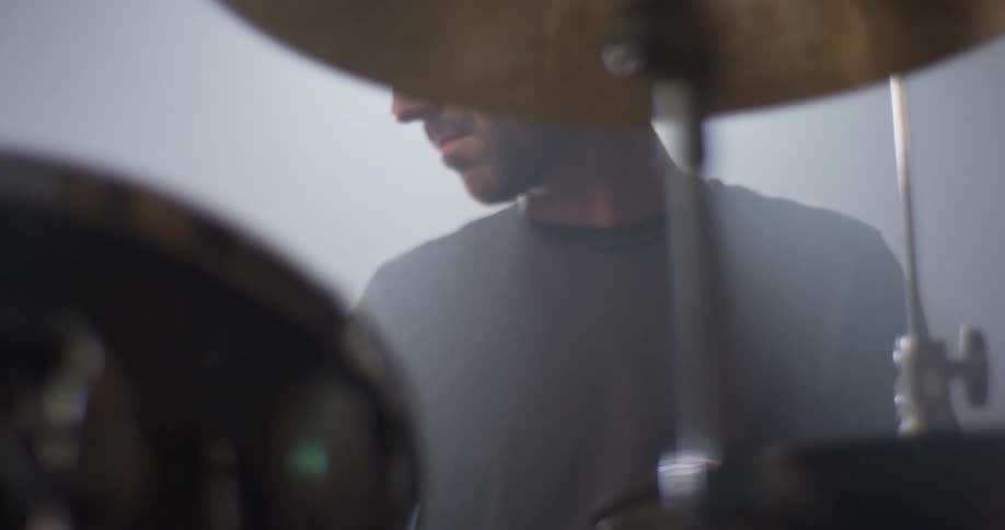 Man drums on a drum set and bobs his head