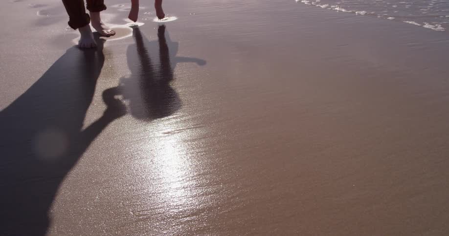 A man and child walk on the wet sand