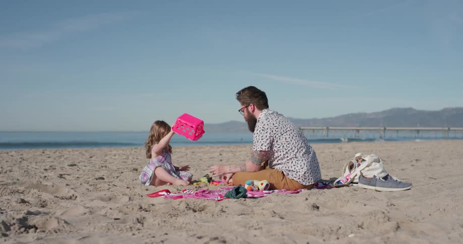 Man and  young child play on the beach