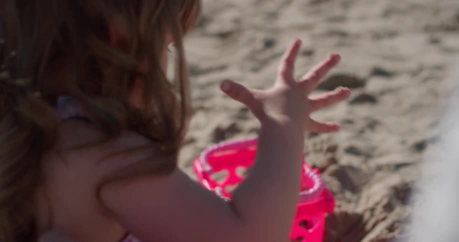 A young girl plays in the sand on the beach