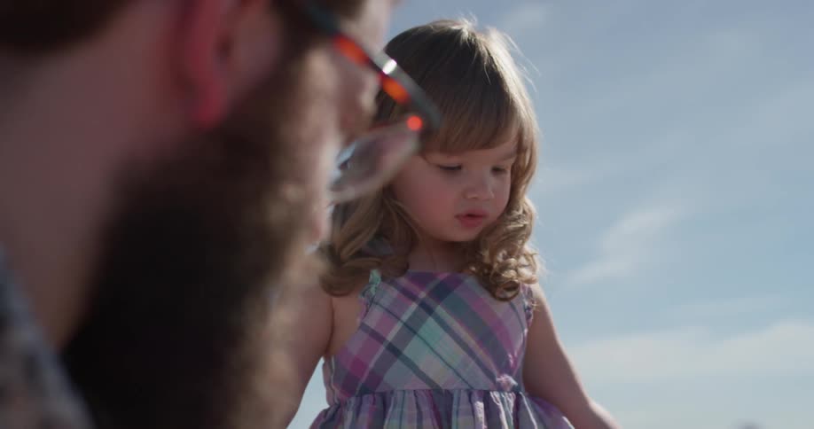 Toddler talks to a man outside on a sunny day