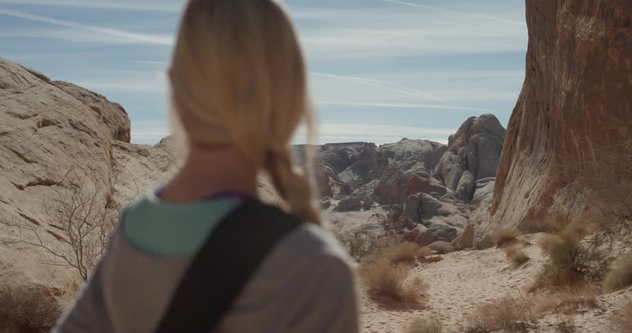 Woman smiles and looks up while standing outside by rocky terrain