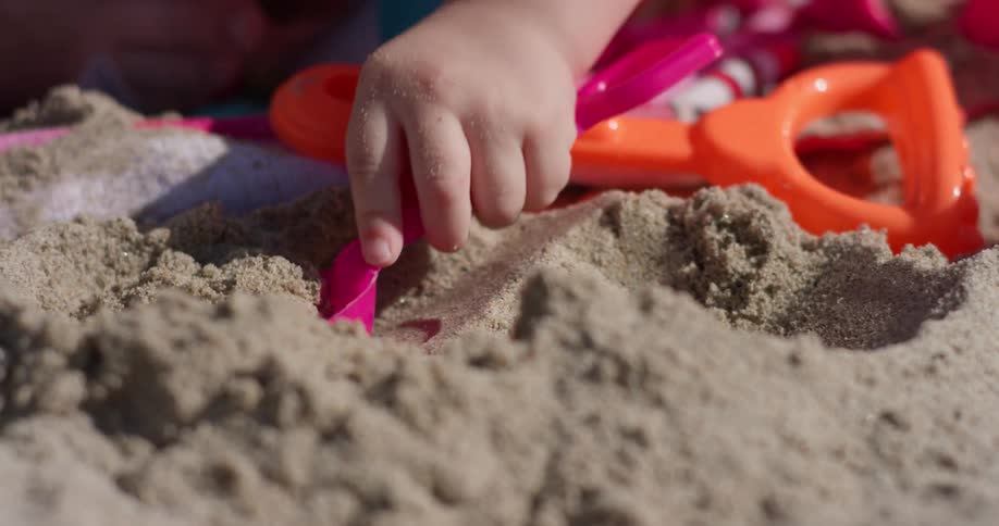 A young girl plays on the beach with plastic toys