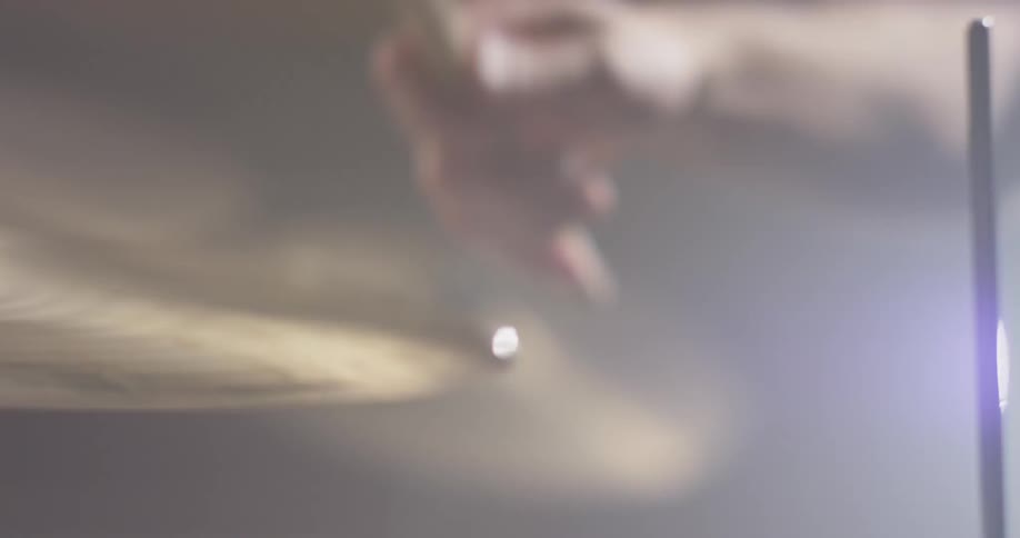 Hand holding a drum stick hits a cymbal repeatedly
