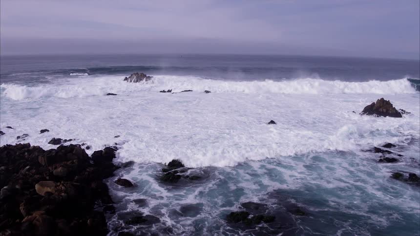 Birds fly above the crashing waves