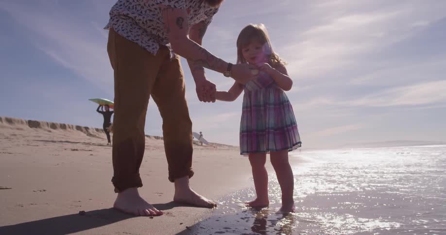 Father plays with daughter at ocean's edge