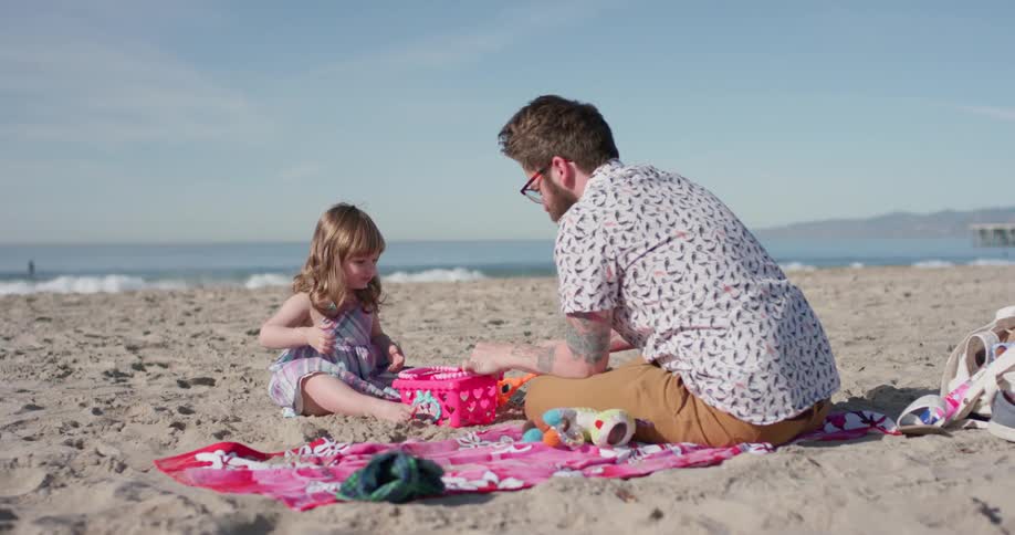 A man plays with a young girl on the beach