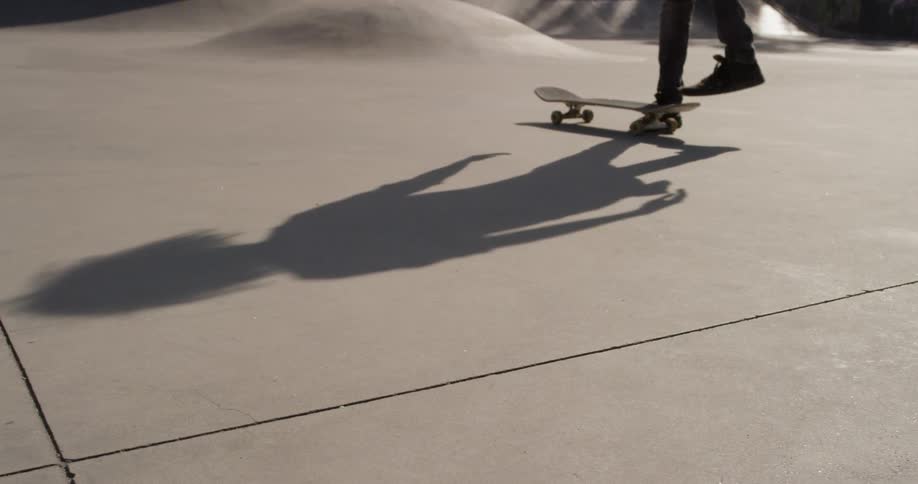 A man picks up a skateboard at an outdoor skatepark
