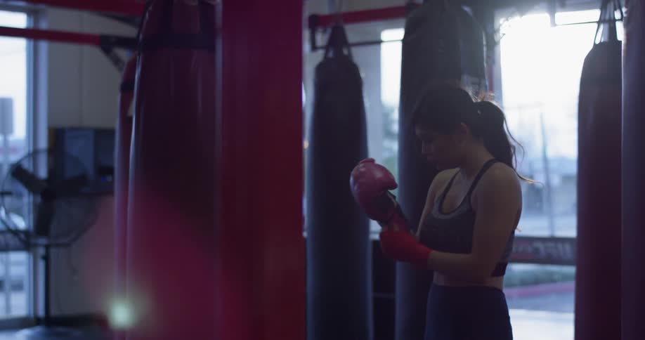 A woman puts on boxing gloves inside a gym