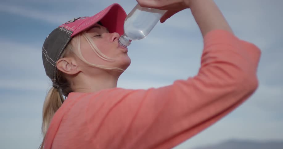 The woman drinks a bottle of water