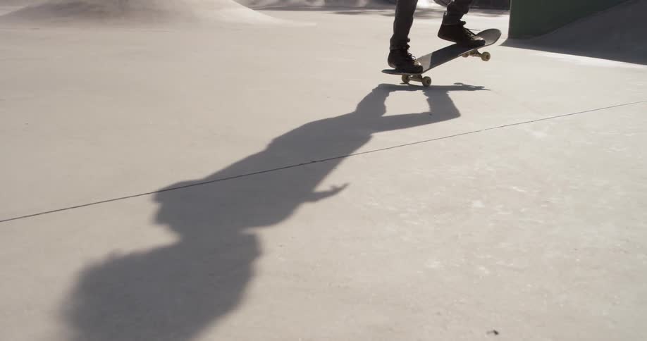 Man flips his skateboard as he rides it on a sunny day