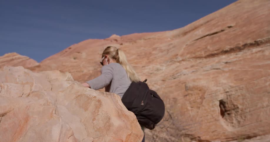 A woman climbs up rocks in a desert