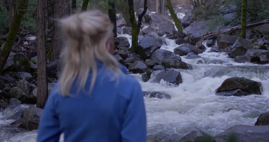 A woman stands by the flowing rapids