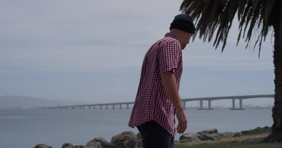Man in a checkered shirt pushes himself on a trail near the ocean