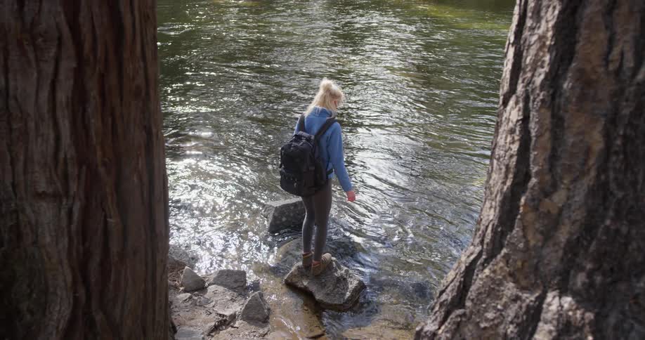 Woman walks on rocky terrain next to a river