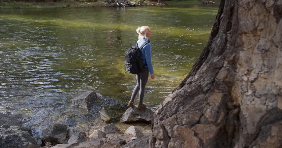 A woman stands on a rock by the river
