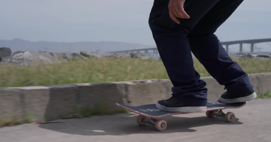 A person rides his skateboard then does a jump