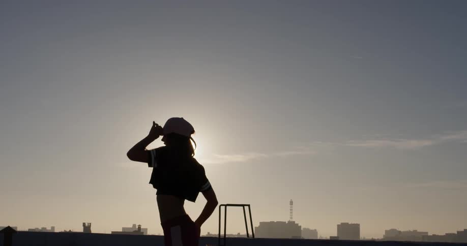 A woman dances on a building rooftop