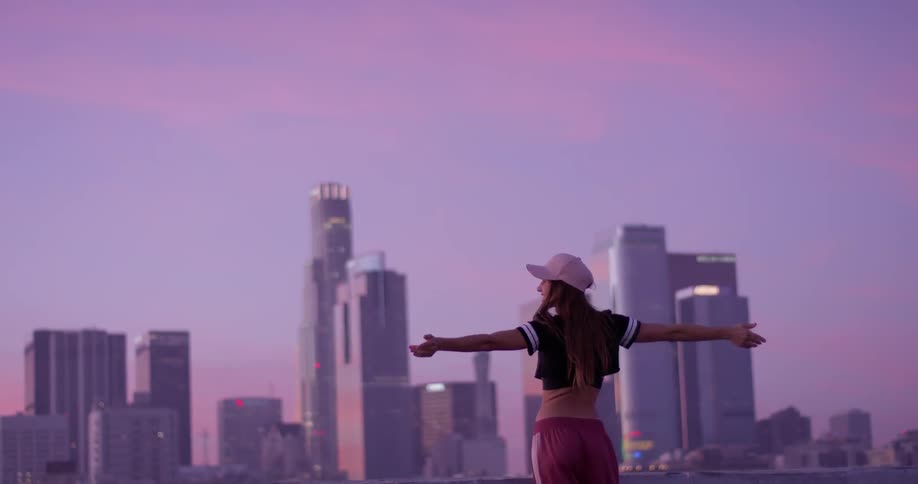A woman out stretches her arms on the rooftop
