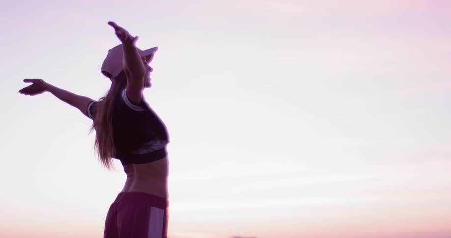 Woman raises her arms standing outside in nature