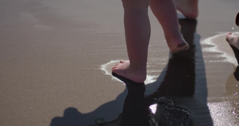 A man and young girl walk on the wet sand